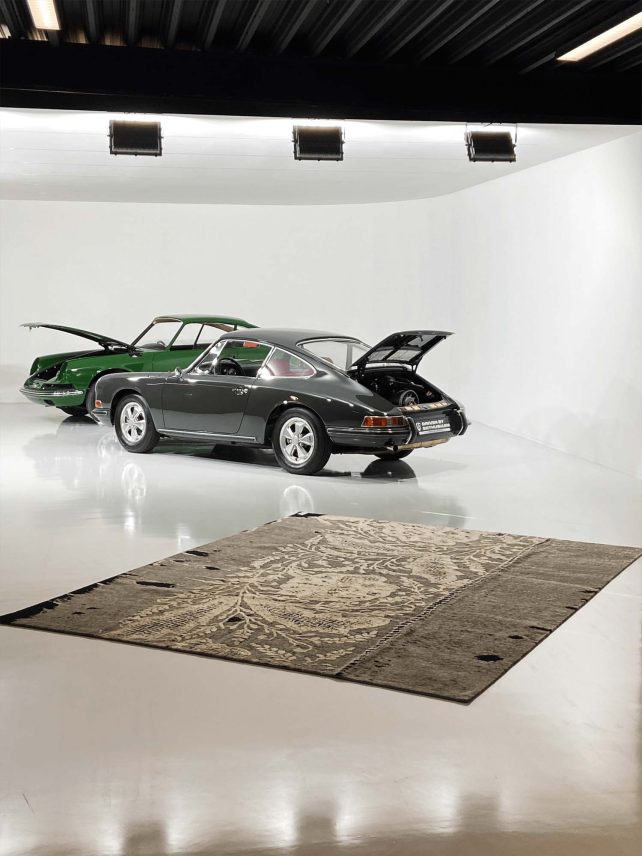 Grauer Geba Teppich "Dalma" mit weißem floralem Muster aus Seide vor zwei Oldtimer Porsche 911 - Geba Teppich