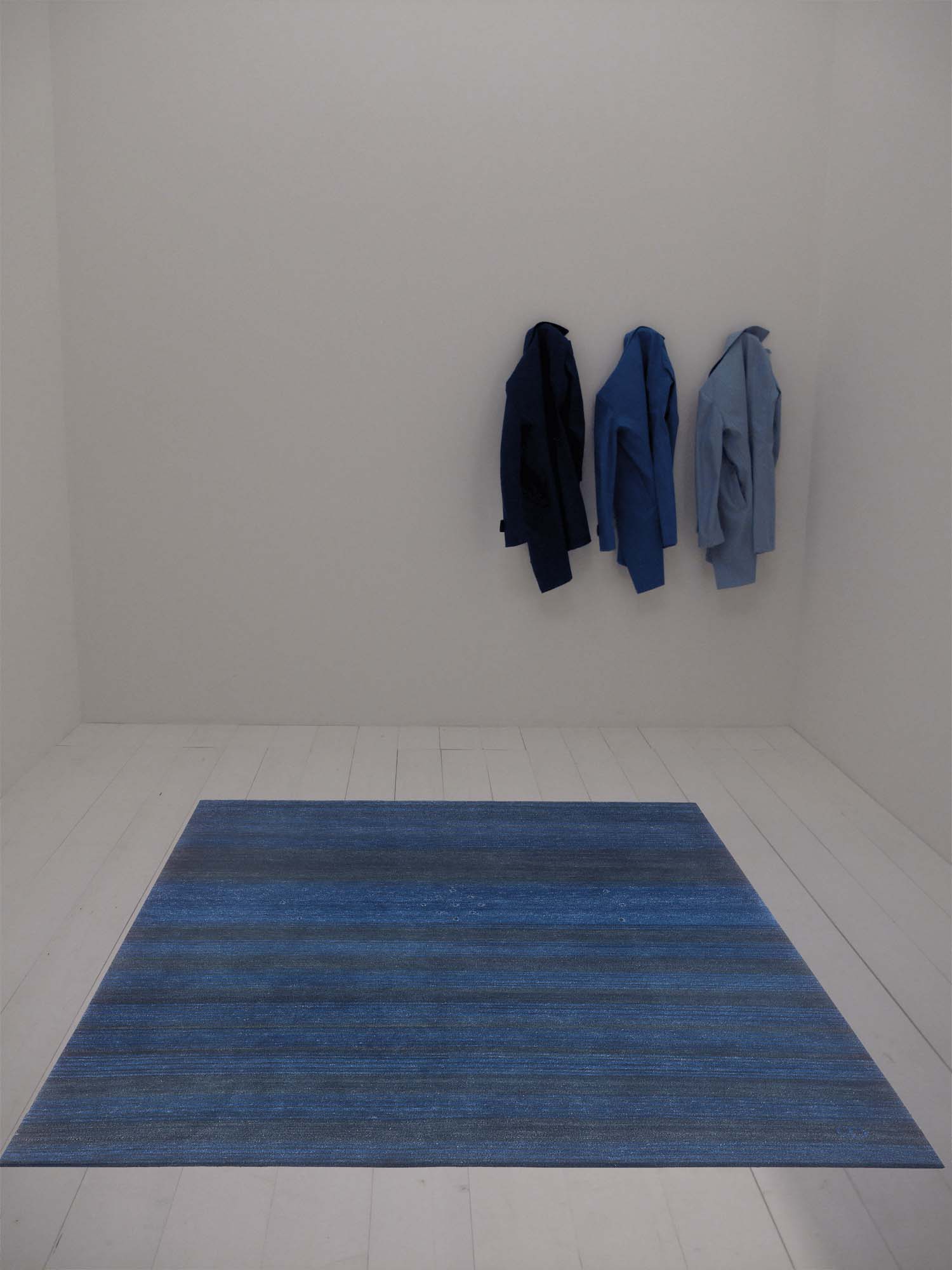 Leerer Raum mit 3 Hemden in unterschiedlichen Blautönen und Geba Teppich "Kumra blue" - Geba Teppich