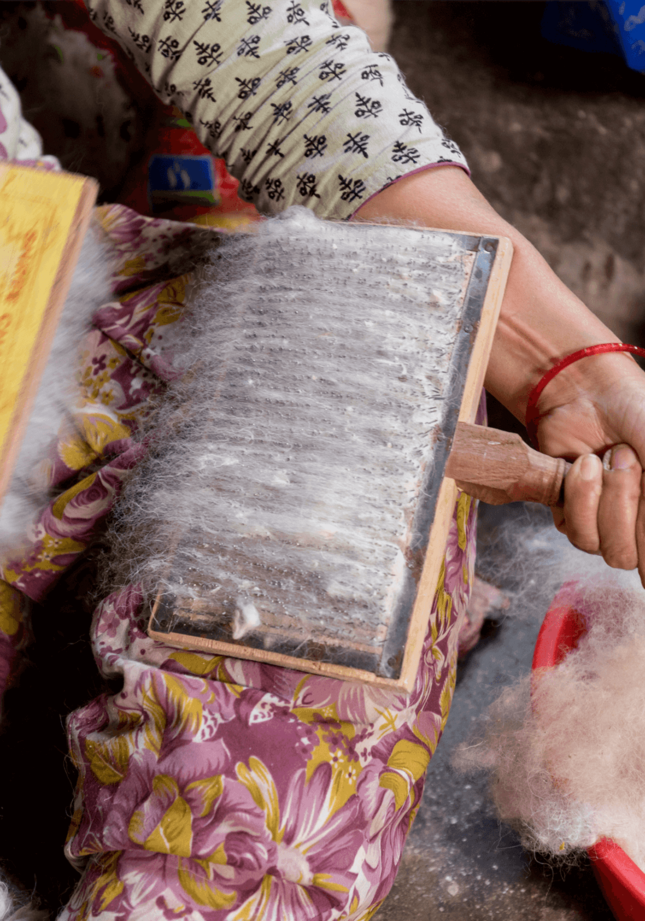 Per Hand wird die Wolle in Nepal gebürstet bzw. kapiert bevor sie zu einem Wollfaden versponnen wird - Geba Teppich